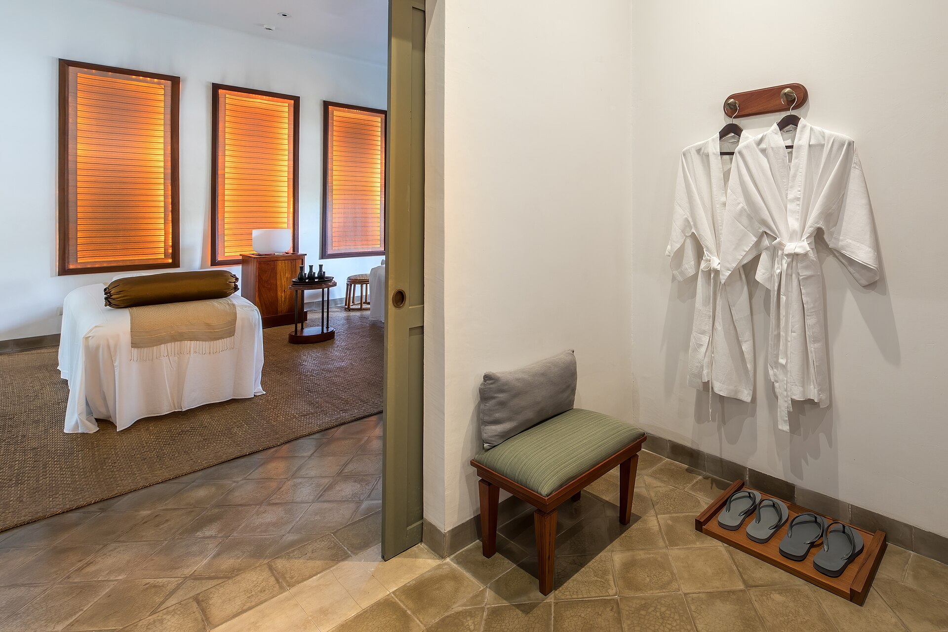 Private resort spa treatment room with robes and massage bed